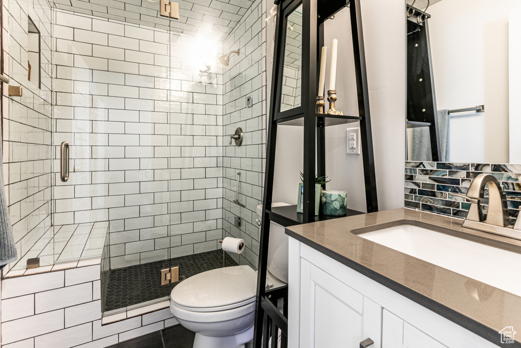 Bathroom featuring tasteful backsplash, walk in shower, toilet, tile floors, and vanity