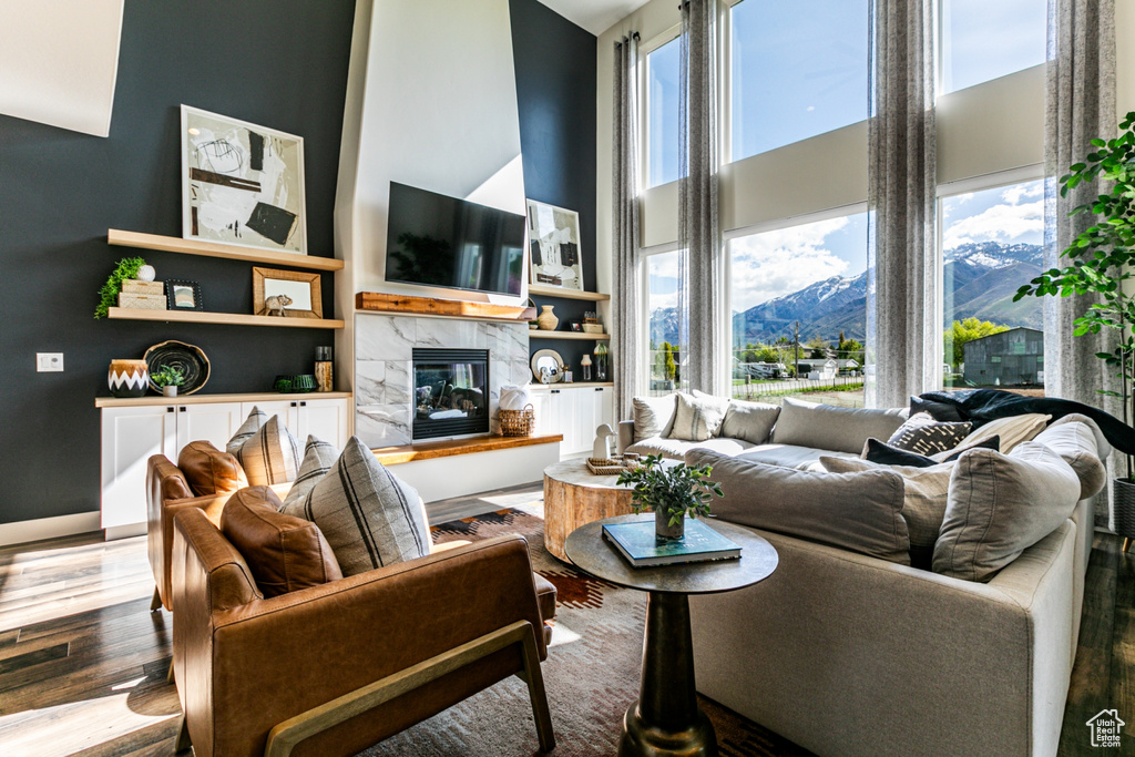 Living room featuring hardwood / wood-style flooring, a high end fireplace, a mountain view, and a high ceiling