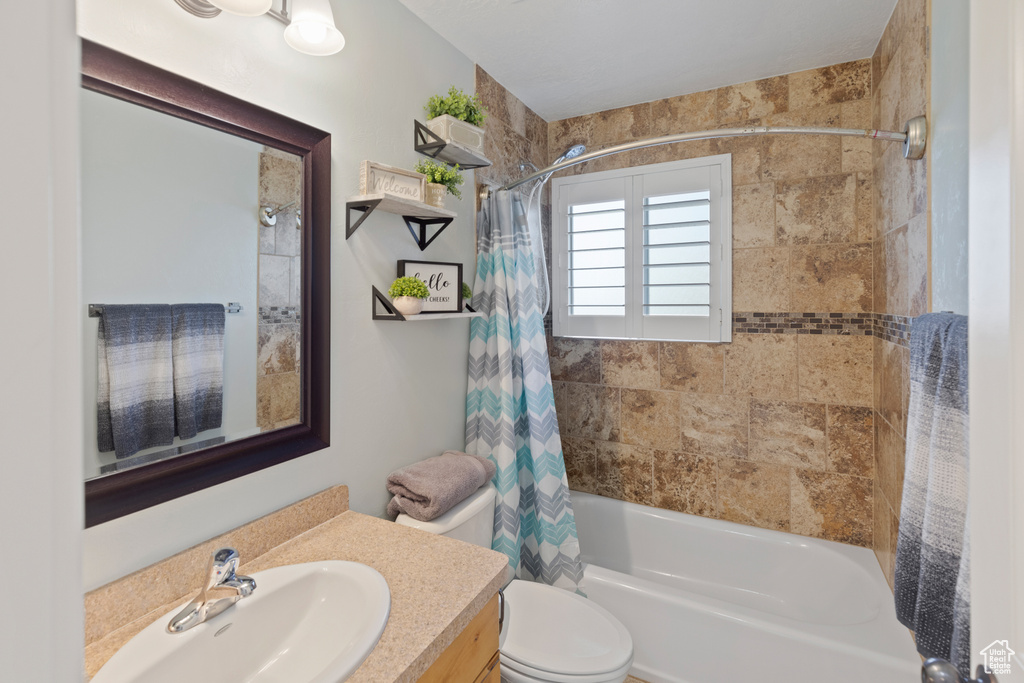 Full bathroom featuring vanity, toilet, and shower / tub combo with curtain