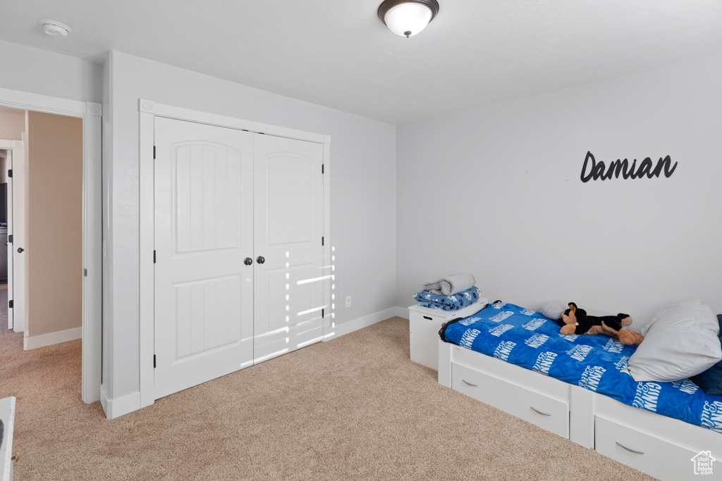 Bedroom with light carpet and a closet