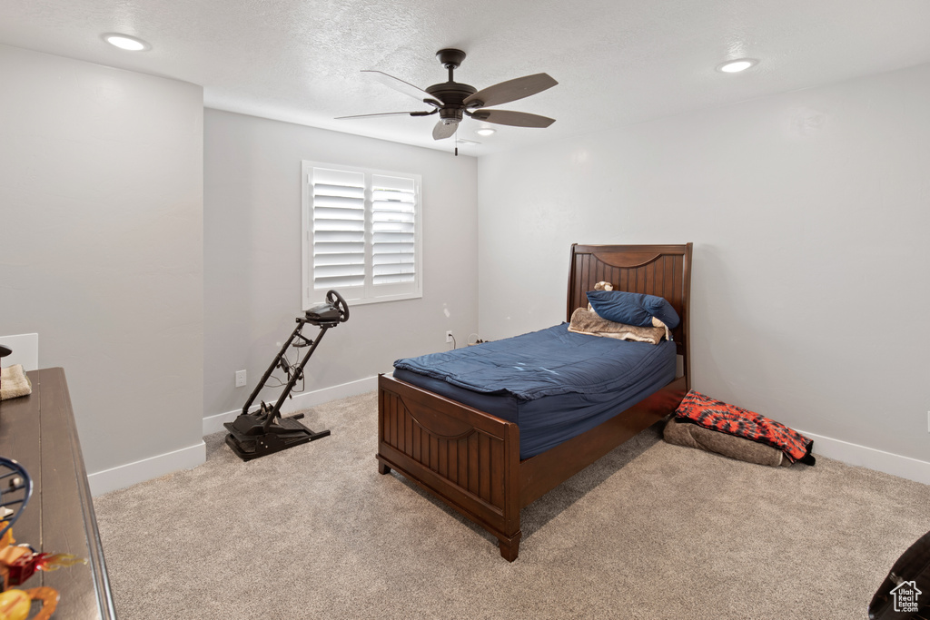 Carpeted bedroom with ceiling fan and a textured ceiling