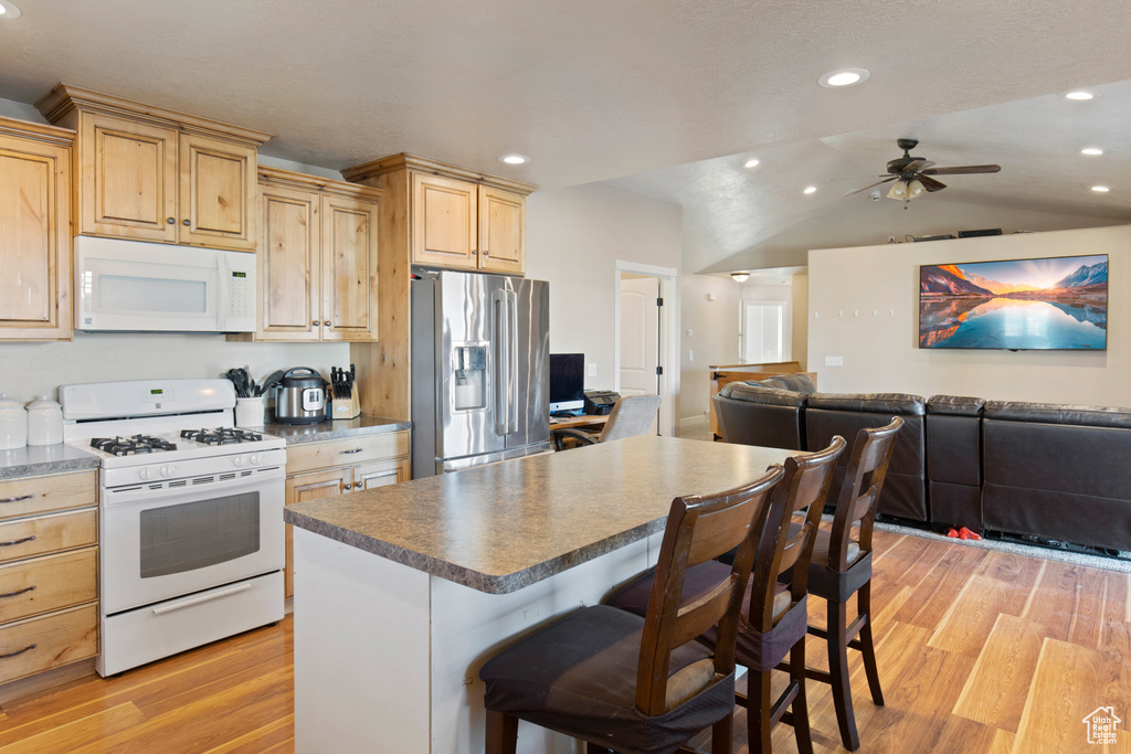 Kitchen with a kitchen island, white appliances, ceiling fan, vaulted ceiling, and light hardwood / wood-style floors