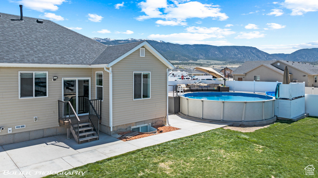 Rear view of property featuring a mountain view, a yard, and a fenced in pool