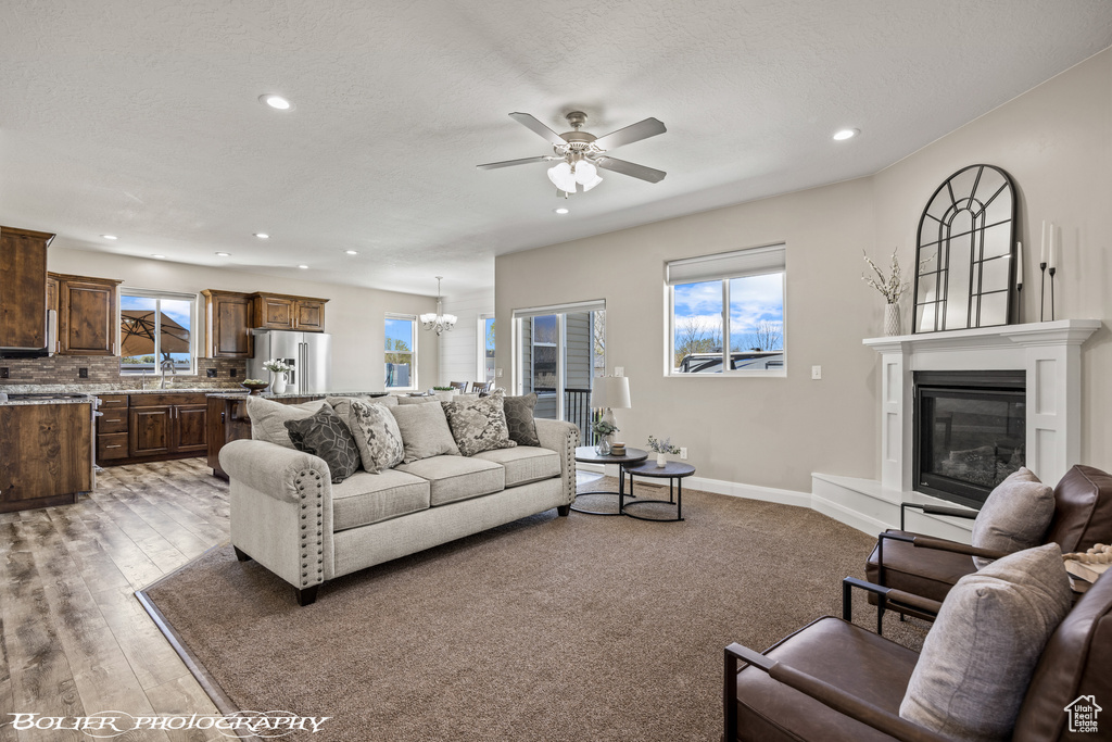 Living room with light colored carpet and ceiling fan with notable chandelier