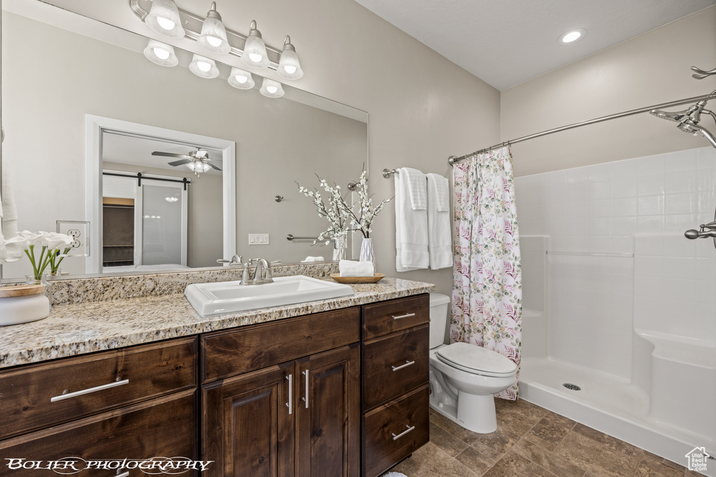 Bathroom with ceiling fan, toilet, a shower with curtain, vanity, and tile floors