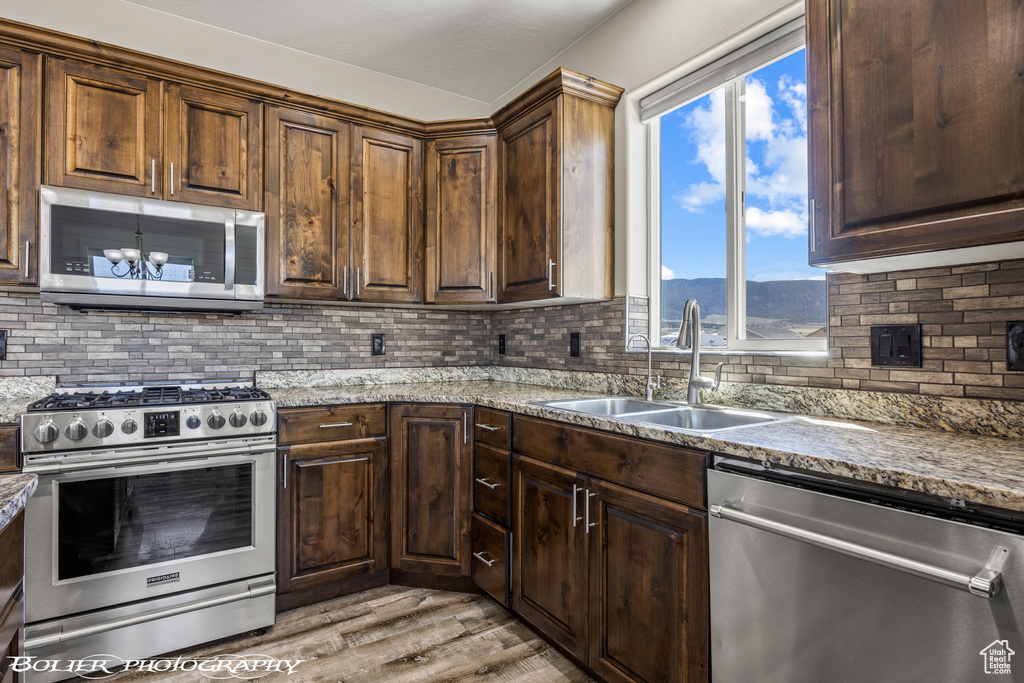 Kitchen with a mountain view, sink, backsplash, light wood-type flooring, and stainless steel appliances