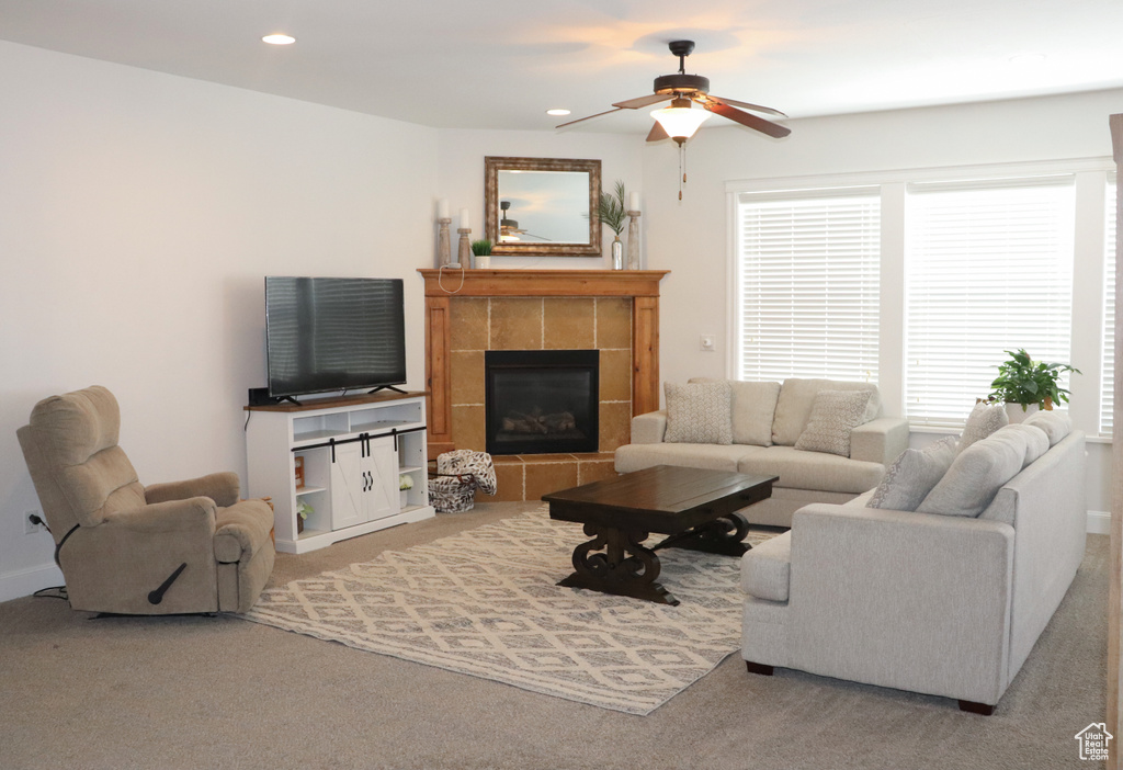 Living room featuring ceiling fan, a tile fireplace, and carpet floors