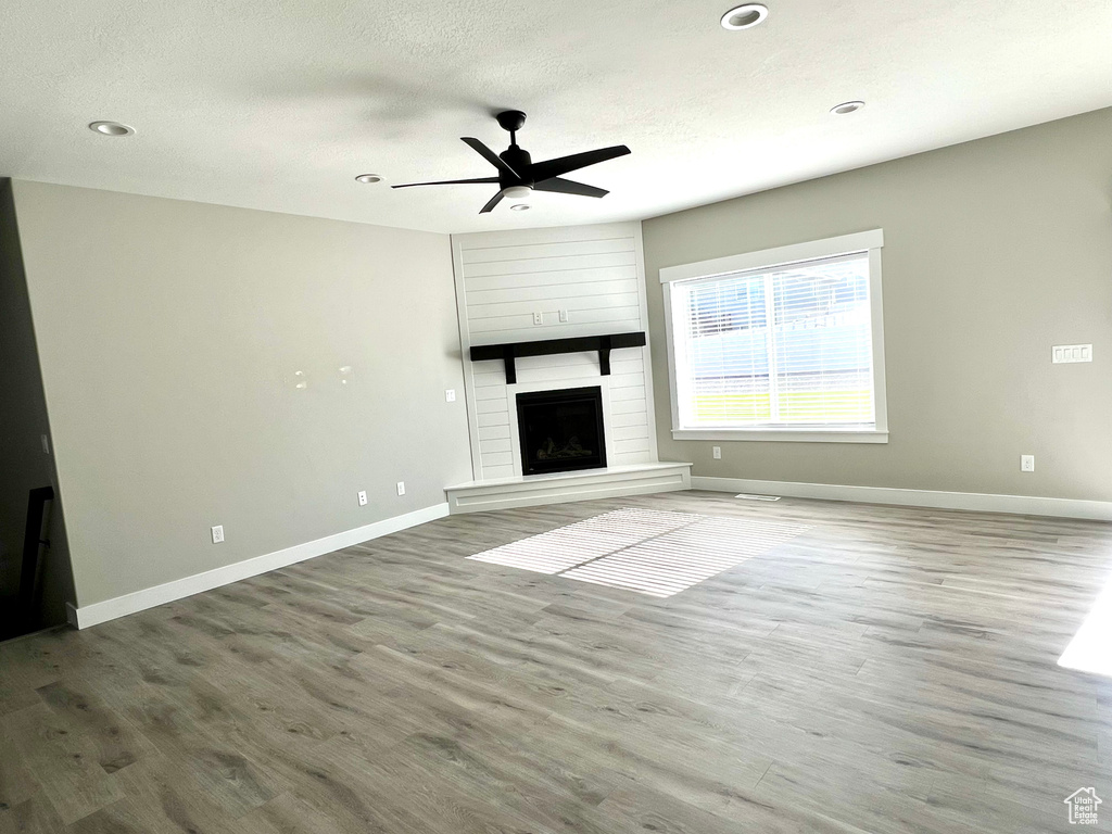 Unfurnished living room featuring ceiling fan, hardwood / wood-style flooring, and a fireplace
