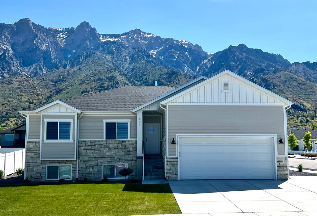 View of front of home with a mountain view, a garage, and a front yard