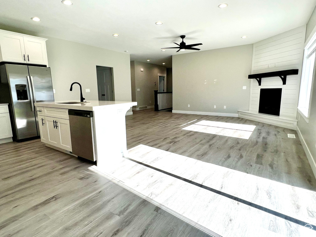 Kitchen featuring a large fireplace, sink, light hardwood / wood-style flooring, and stainless steel appliances