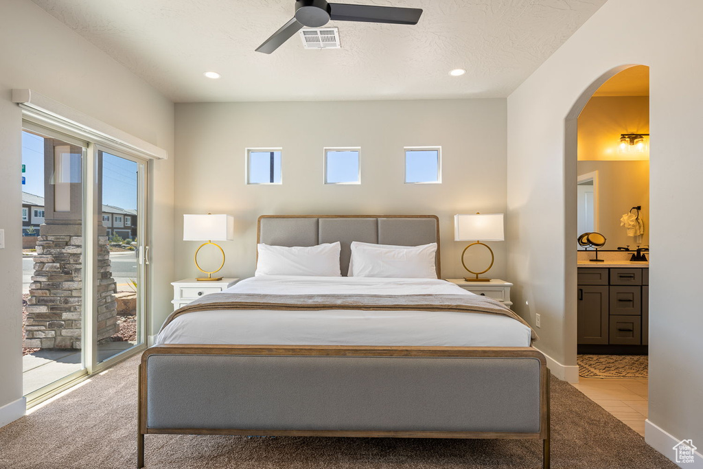 Bedroom featuring light colored carpet, ensuite bath, ceiling fan, and access to exterior