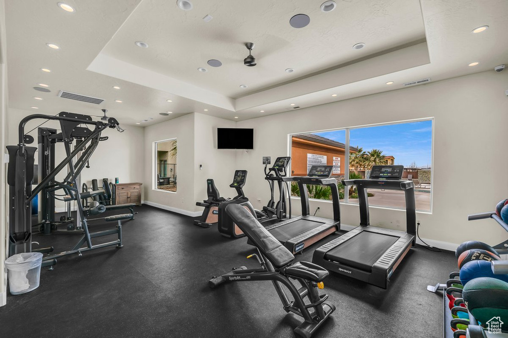 Workout area with ceiling fan and a raised ceiling
