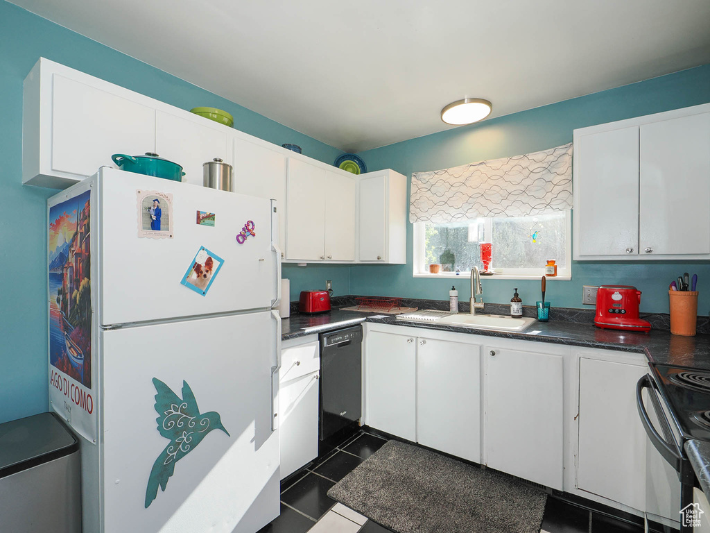 Kitchen featuring white fridge, dishwasher, electric range, dark tile flooring, and sink
