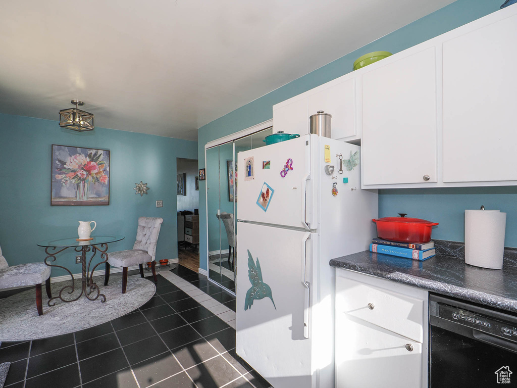 Kitchen with white fridge, dishwasher, white cabinets, and dark tile floors