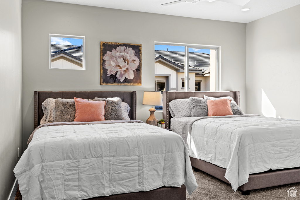 Bedroom with carpet flooring, ceiling fan, and multiple windows