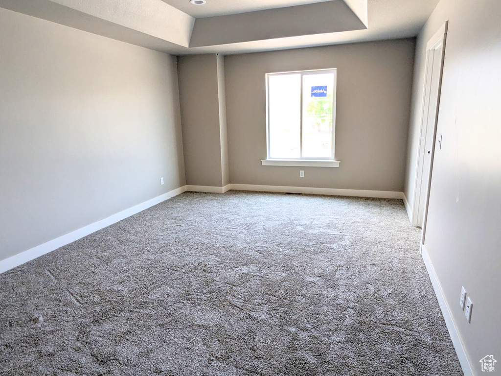 Unfurnished room with carpet flooring and a tray ceiling