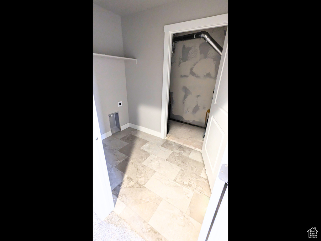 Clothes washing area featuring hookup for an electric dryer and light tile patterned floors