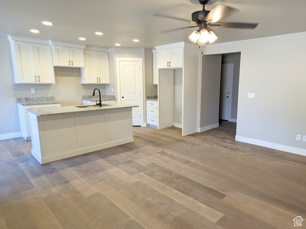 Kitchen featuring white cabinetry, ceiling fan, light hardwood / wood-style floors, light stone countertops, and sink