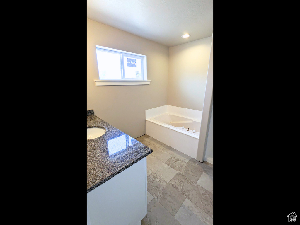 Bathroom with vanity, tile patterned flooring, and a bathing tub