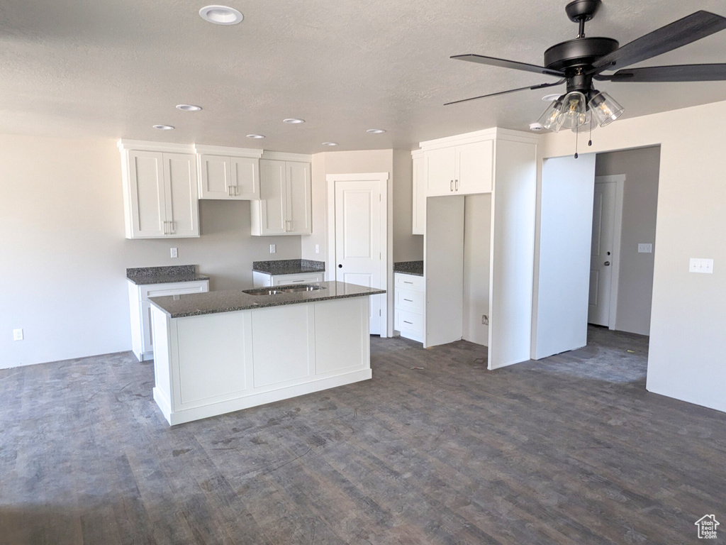 Kitchen featuring a kitchen island, dark wood-type flooring, ceiling fan, and white cabinets