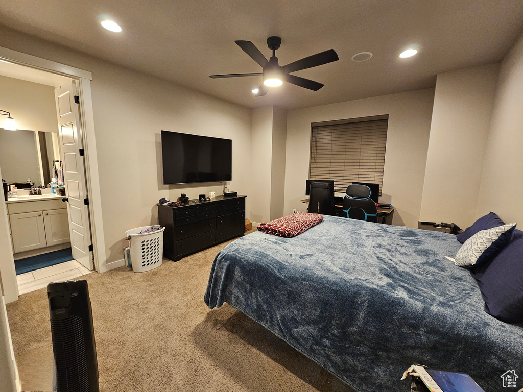 Bedroom with ensuite bath, light colored carpet, ceiling fan, and sink