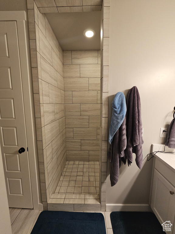 Bathroom featuring tiled shower, vanity, and tile floors