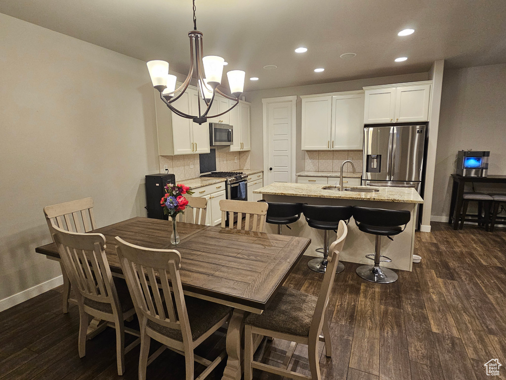 Dining space with sink, dark hardwood / wood-style flooring, and an inviting chandelier