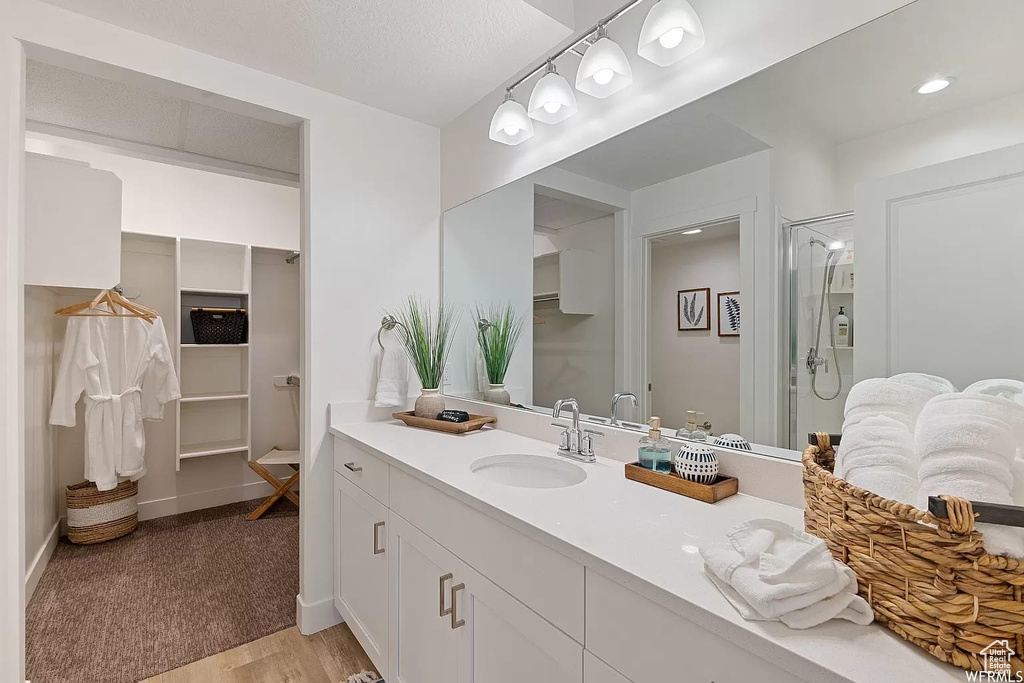 Bathroom featuring hardwood / wood-style floors, a shower, and large vanity