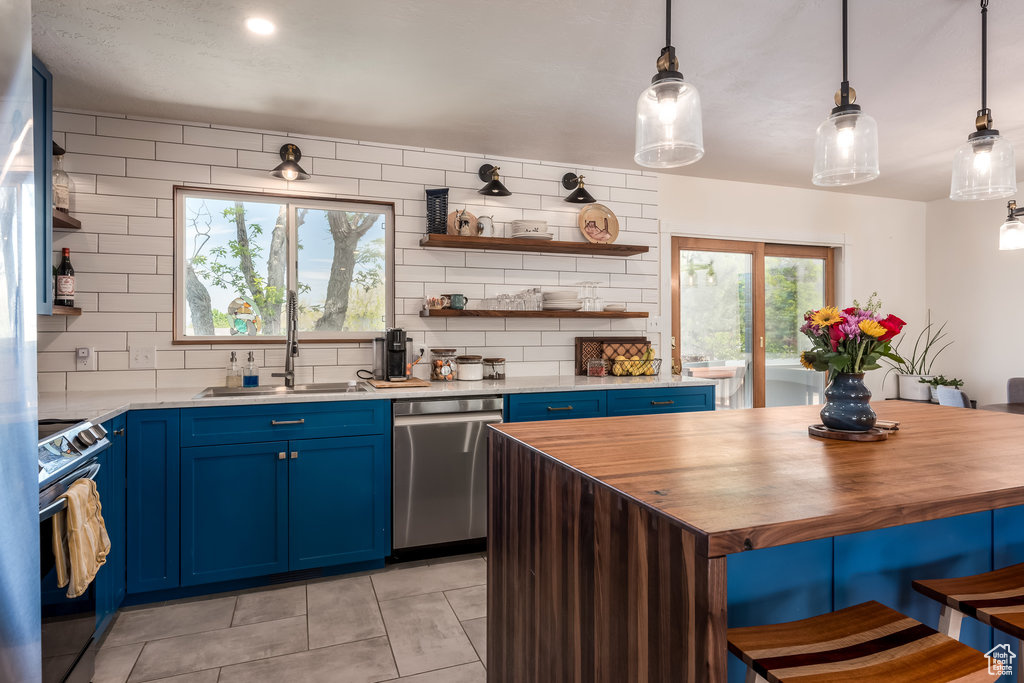 Kitchen with stainless steel dishwasher, tasteful backsplash, butcher block counters, electric range, and blue cabinets