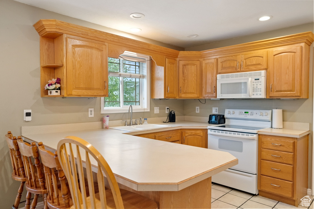 Kitchen featuring sink, white appliances, kitchen peninsula, and light tile flooring