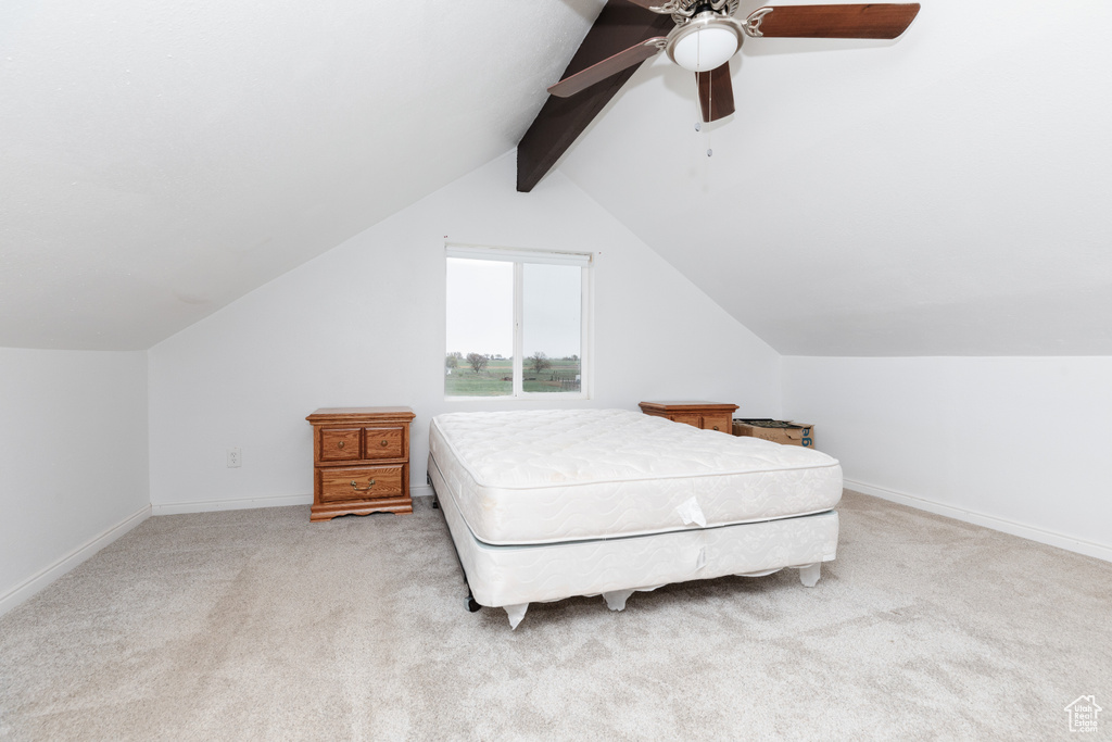 Carpeted bedroom featuring ceiling fan and vaulted ceiling with beams