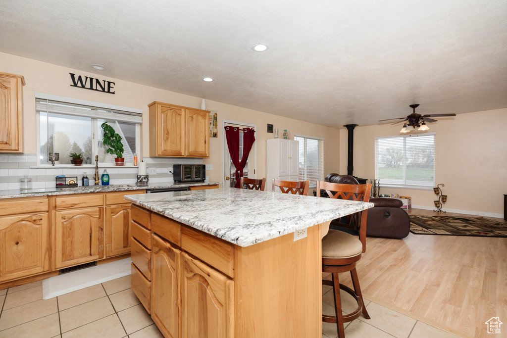 Kitchen featuring a kitchen island, ceiling fan, light hardwood / wood-style floors, sink, and a breakfast bar
