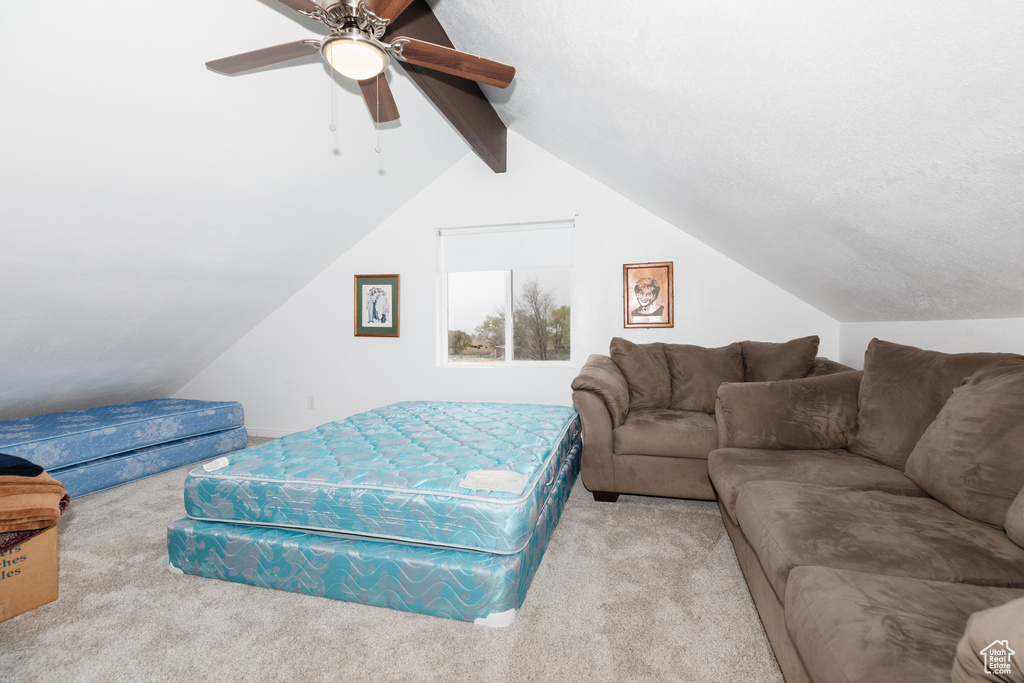 Carpeted living room with ceiling fan and vaulted ceiling with beams