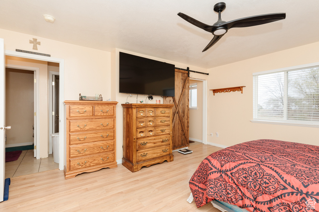 Bedroom featuring wood-type flooring, ceiling fan, and a barn door