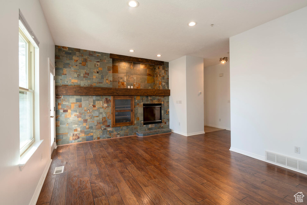 Unfurnished living room with a large fireplace, a wealth of natural light, and dark hardwood / wood-style floors