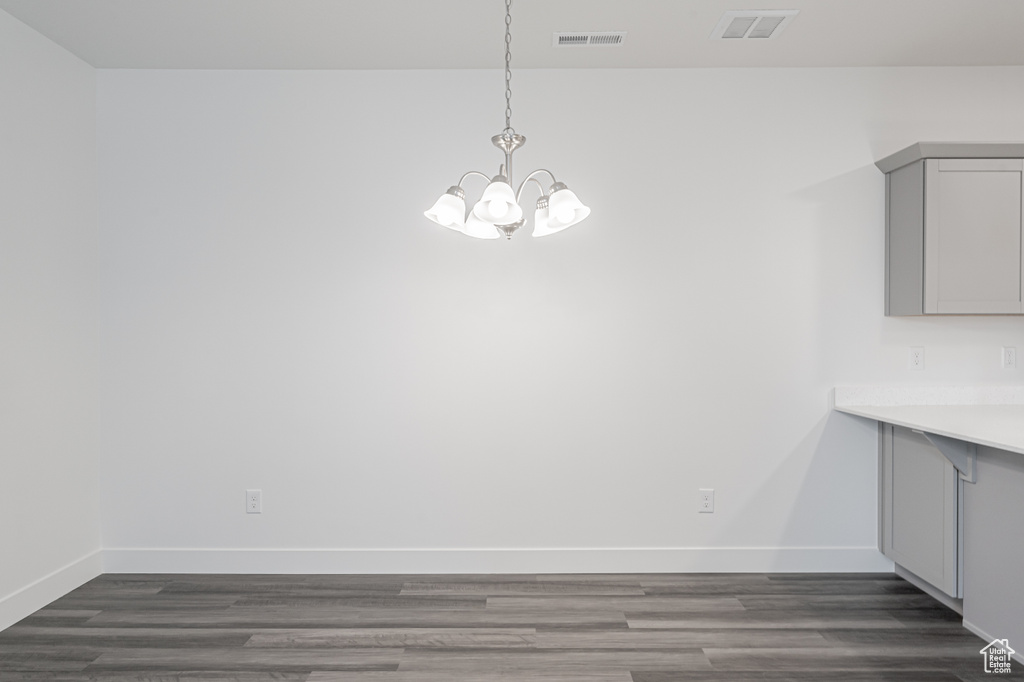 Unfurnished dining area featuring dark hardwood / wood-style flooring and an inviting chandelier
