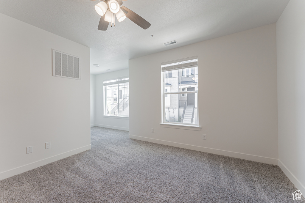 Unfurnished room with a textured ceiling, carpet flooring, and ceiling fan