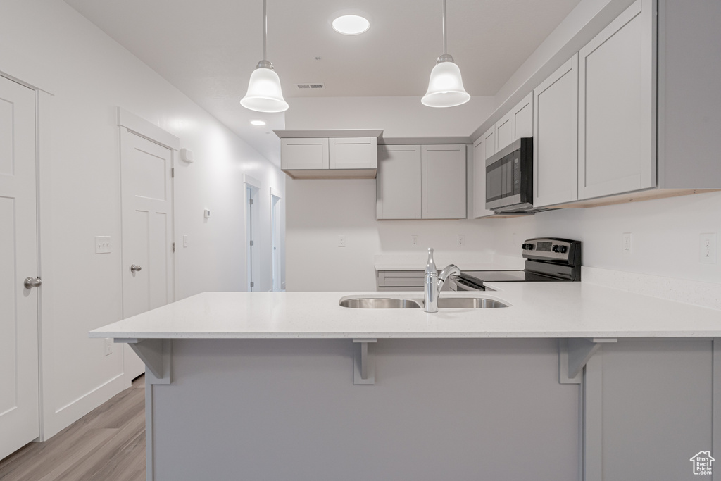 Kitchen with electric range oven, sink, hanging light fixtures, and a breakfast bar