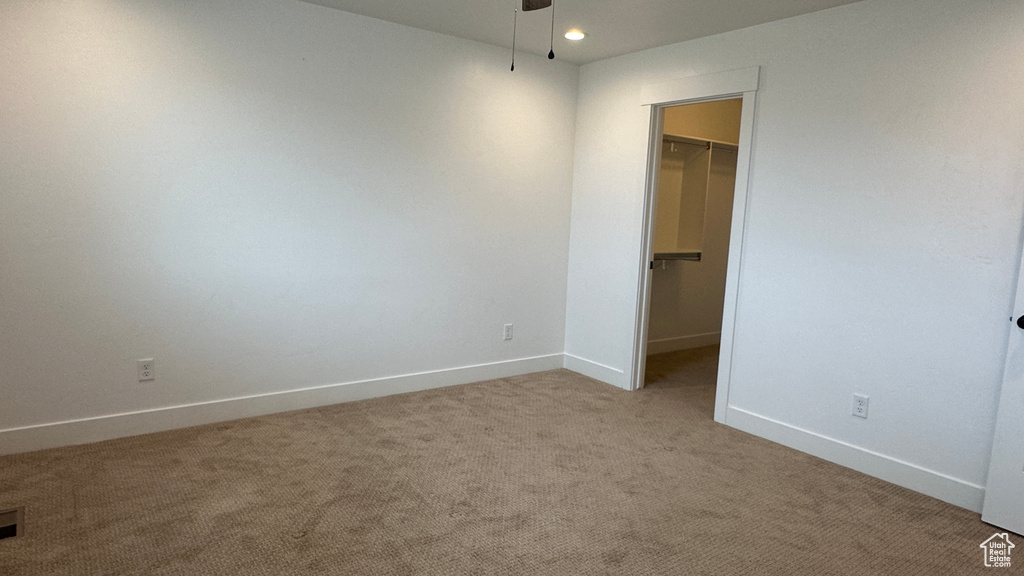 Unfurnished bedroom featuring carpet flooring, a closet, and a spacious closet