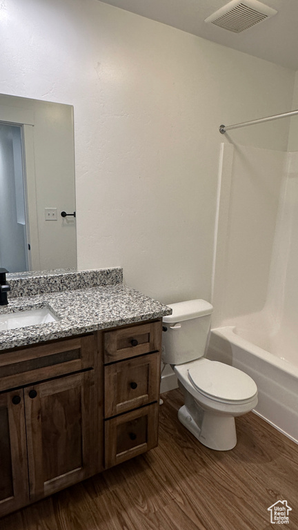 Full bathroom featuring hardwood / wood-style floors, vanity, toilet, and shower / washtub combination