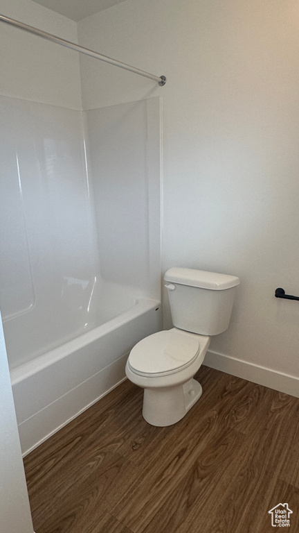 Bathroom with hardwood / wood-style flooring, tub / shower combination, and toilet