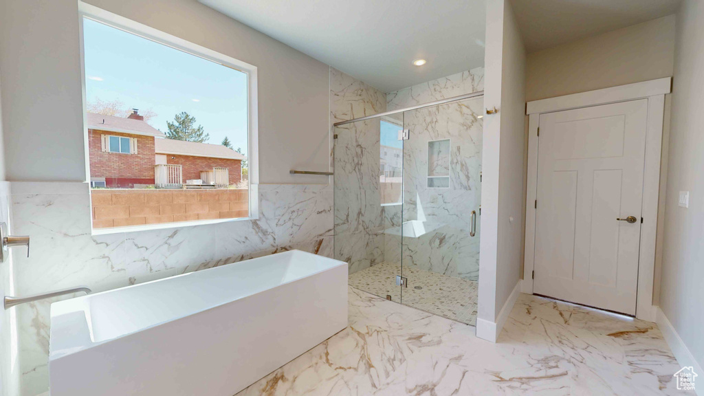 Bathroom with tile flooring, tile walls, and plus walk in shower
