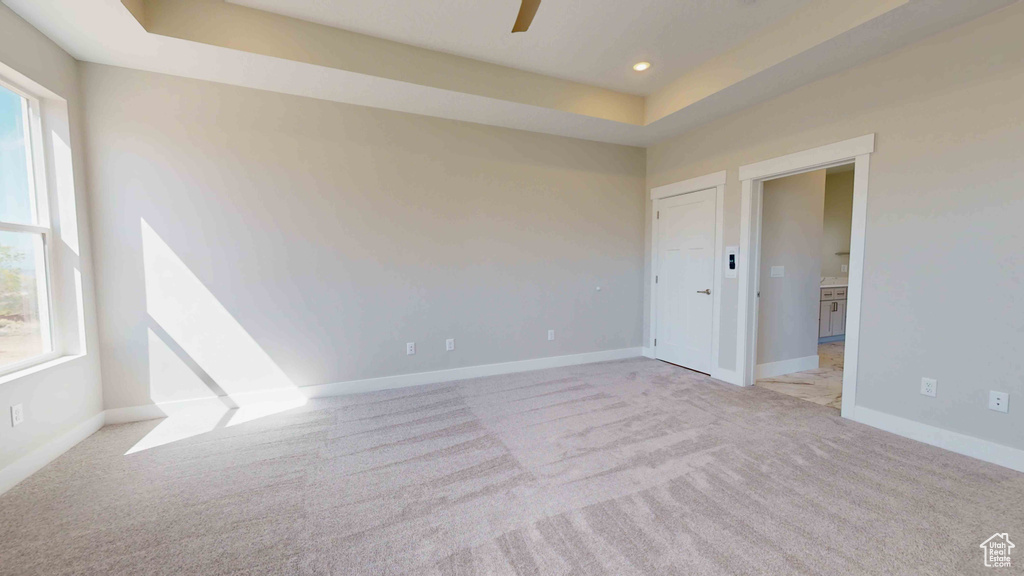 Empty room featuring light colored carpet and a tray ceiling