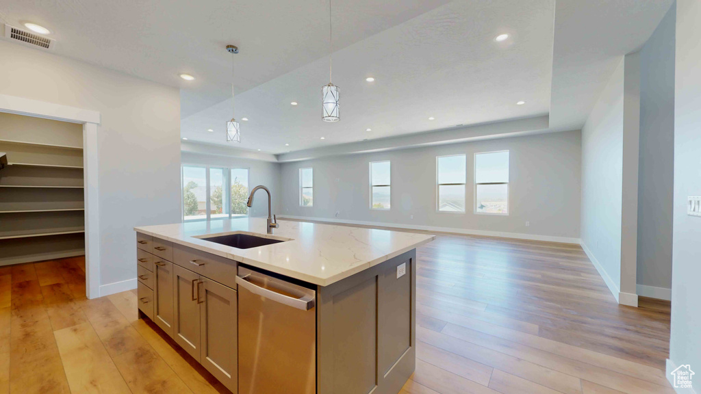 Kitchen featuring decorative light fixtures, dishwasher, a kitchen island with sink, sink, and light wood-type flooring