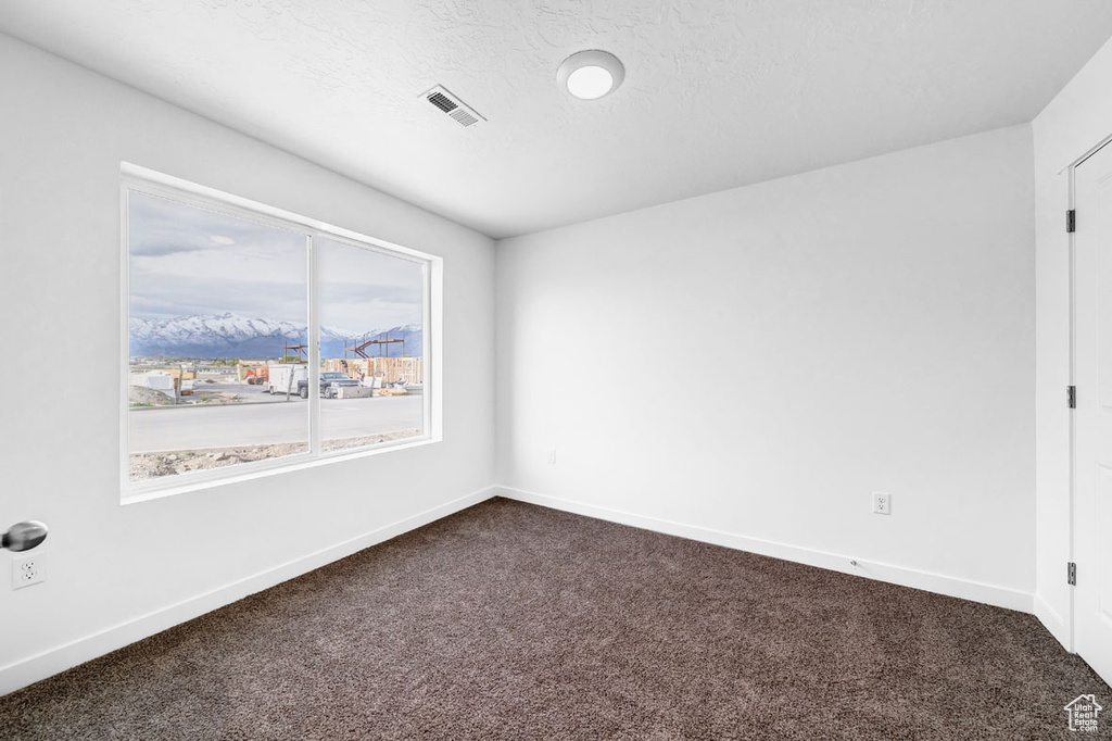 Unfurnished room featuring a mountain view and dark carpet