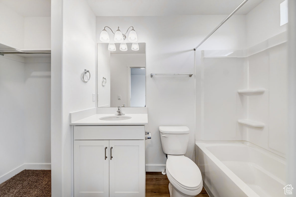 Full bathroom featuring bathtub / shower combination, hardwood / wood-style floors, large vanity, and toilet
