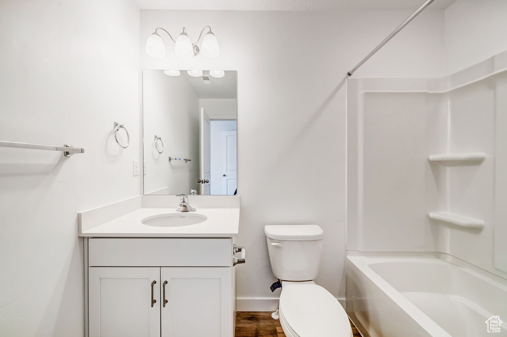 Full bathroom with hardwood / wood-style floors, washtub / shower combination, oversized vanity, and toilet