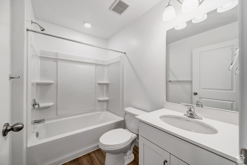 Full bathroom with shower / washtub combination, vanity, hardwood / wood-style flooring, and toilet