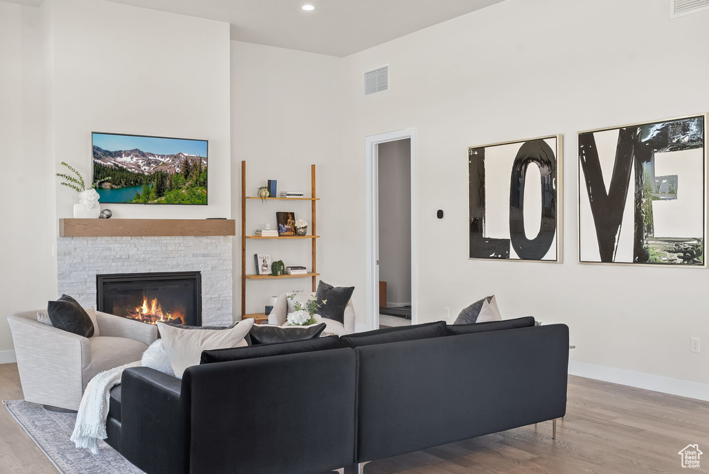 Living room with a stone fireplace and hardwood / wood-style flooring