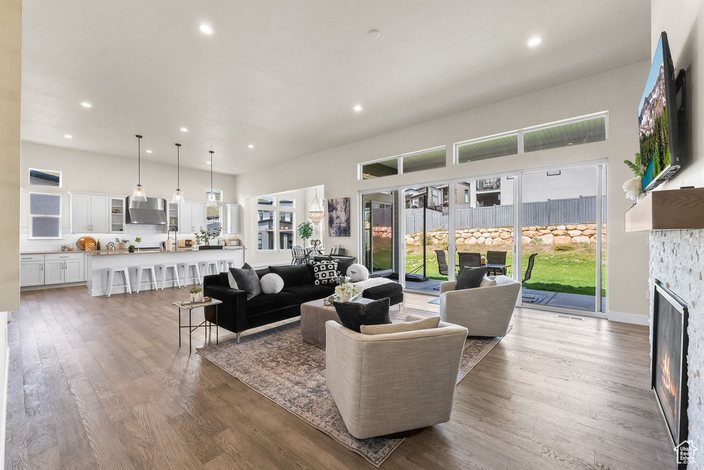 Living room with light hardwood / wood-style floors, a healthy amount of sunlight, and a stone fireplace